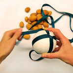 Увиваме лентата около топката, кръстосваме я и завързваме на възел, като оставяме достатъчна дължина от панделката, за да виси топката.