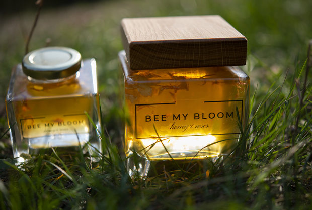 BEE MY BLOOM е изцяло български биологично чист продукт, който носи поезията на отминали времена, създаден е с дълбоко уважение към природата и ресурсите, които тя така щедро ни предоставя.Всичко започва с едно преместване от намерена на тавана книга с рецепти от 1907 г. Рецептата, написана на стар български, е за мед от акация, добит по меките хълмове на Стара планина и розов цвят събиран на изгрев в долините й. Току що набраният свеж розов цвят се потапя на пълнолуние, за да се освободят ароматите му и да се слеят с тези на меда. След три лунни цикли, дъха на благоуханната роза се прехвърля в меда и заедно създават BEE MY BLOOM.Малцина са тези, които са запазили знанието и познават този тайнствен танц от вълнуващи ритми, вдъхновени от аромата и сладостта на българската природа.Това е и началото - тази рецепта и желанието да се направи нещо толкова добро, колкото е било възможно някога, преди времето да се забърза. Проявяваме любопитство, уважение и доверие към миналото, за да може днес да се насладим на сладостта от чисти естествени продукти.BEE MY BLOOM може да бъде приготвен само през юни, когато пчелите са направили първия акациев мед, а в Долината на розите е започнал розоберът. Комбинацията от най-добрия мед и най-уханните рози има само една цел - да създаде вълнуващо преживяване за сетивата. Всяка стъпка на производство, както и всеки отделен елемент, са докоснати от човешка ръка, без намеса на машини и без принуда. Луната получава своето време, за да създаде своето вълшебство, за да се роди през октомври BEE MY BLOOM.Отношението към природата е отразено и в произведеното количество. Има създадени само 1 677 големи и 1010 малки буркана. Всеки един от тях е напълнен и номериран на ръка.Всичко за първия Бакхус Коледен Гурме Базар вижте тук.Научавайте новостите за събитието във Facebook.Купете билет онлайн с намаление тук.